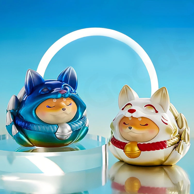 Two colorful fox figurines with blue and gold accents on a reflective surface with a blue gradient background.