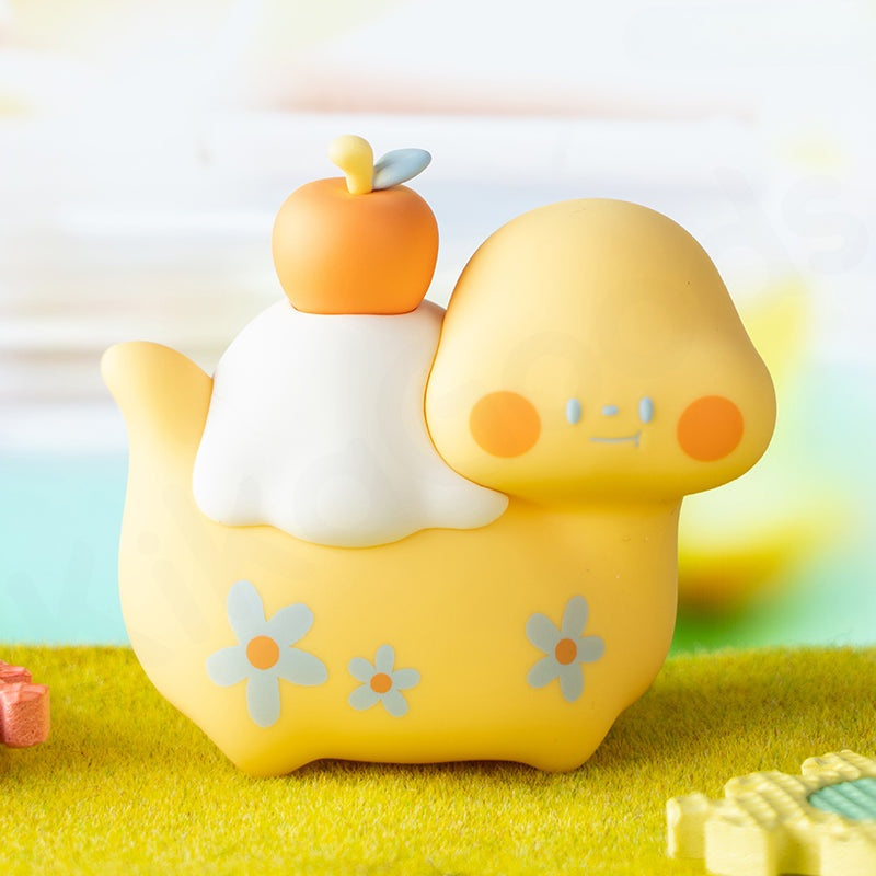 Yellow cartoon-like character with an apple on its head, sitting on a grassy surface with a colorful background.