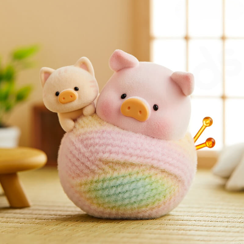 Two plush pig toys on a textured surface with a blurred background