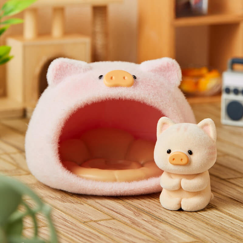 Pink pig-shaped pet bed and toy on a wooden surface