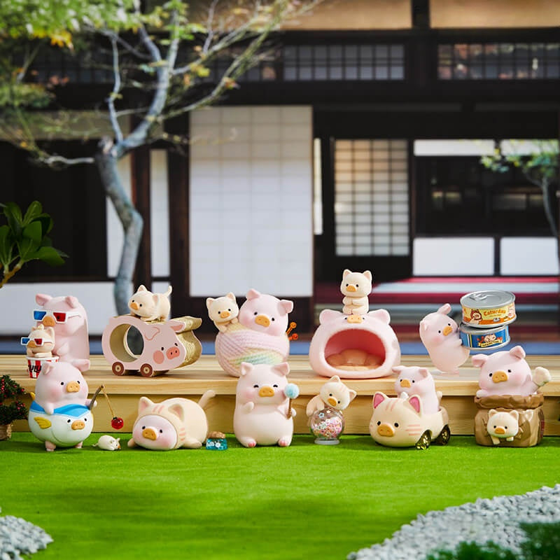 Collection of cute animal figurines in a garden setting with traditional architecture in the background.