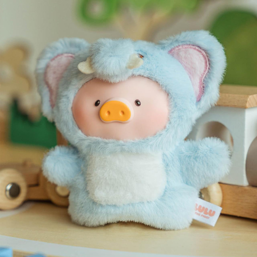 Stuffed toy in a blue bear costume with a visible brand tag on a wooden surface.