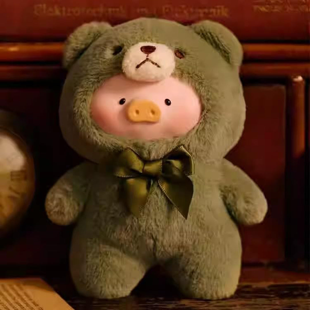 Green teddy bear with a pig costume sitting on a wooden surface.