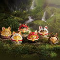 Set of fox-themed figurines with colorful hats in a forest setting