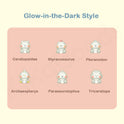 Glow-in-the-dark dinosaur figurines with labels on a pink background