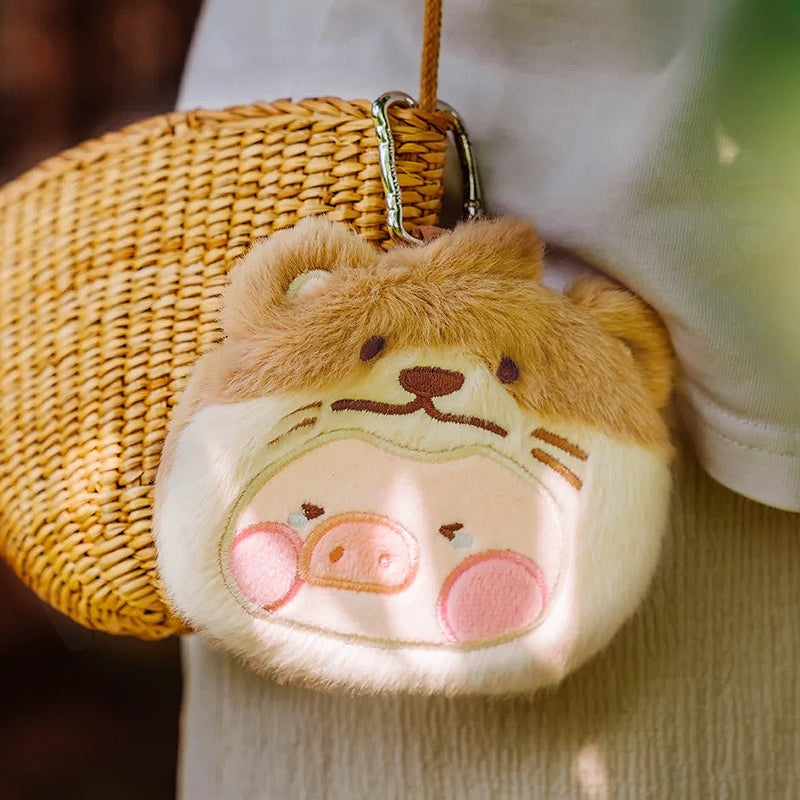 Plush keychain with a cartoonish design of a face with ears and pink cheeks, attached to a woven bag.