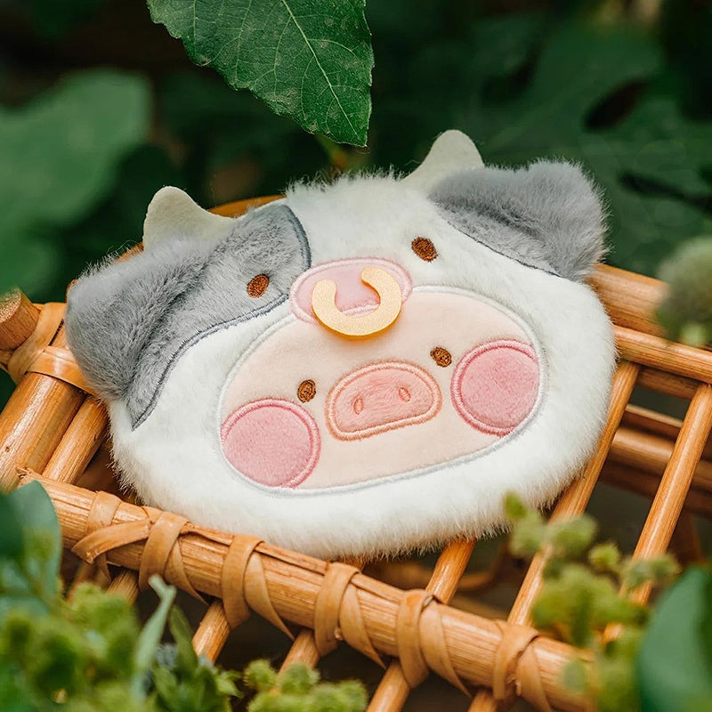 Plush pig toy on a woven surface with green leaves in the background