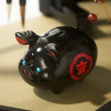 Black pig-shaped object with red design on a beige surface