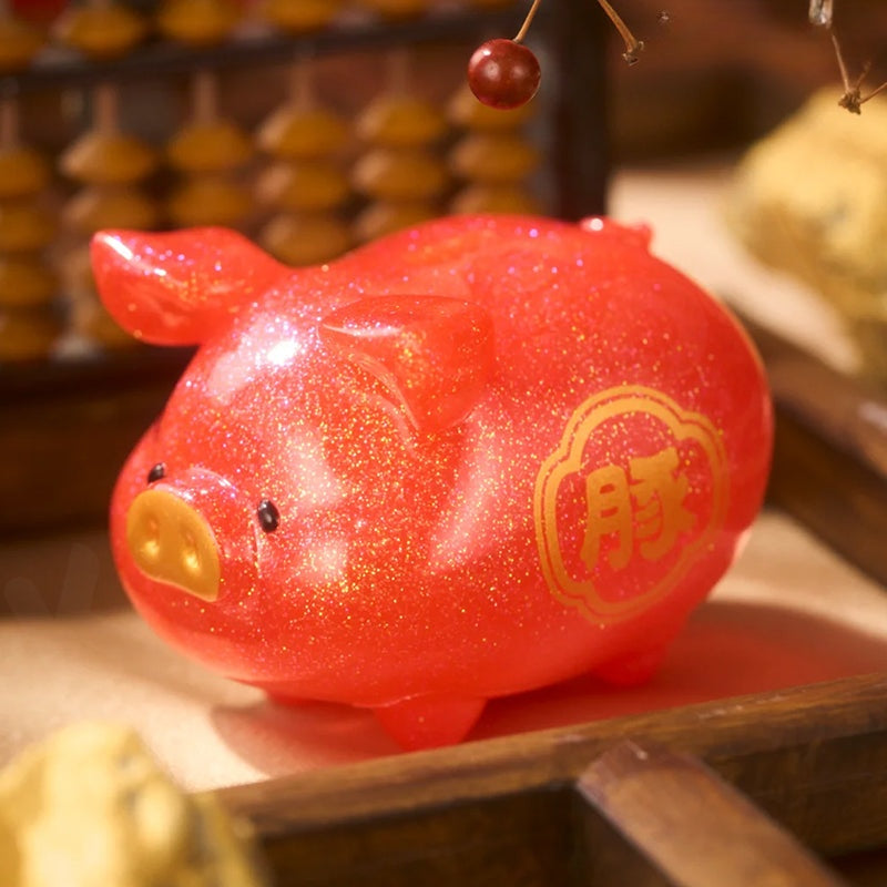 Red glittery pig-shaped ornament with gold accents on a wooden surface.