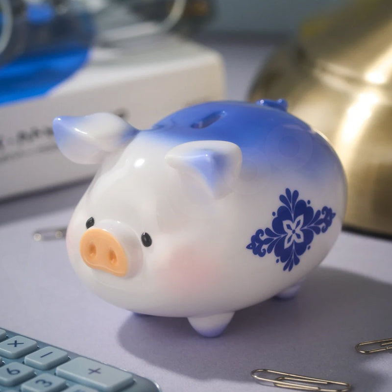 Blue and white piggy bank with a floral design on a desk with office supplies.