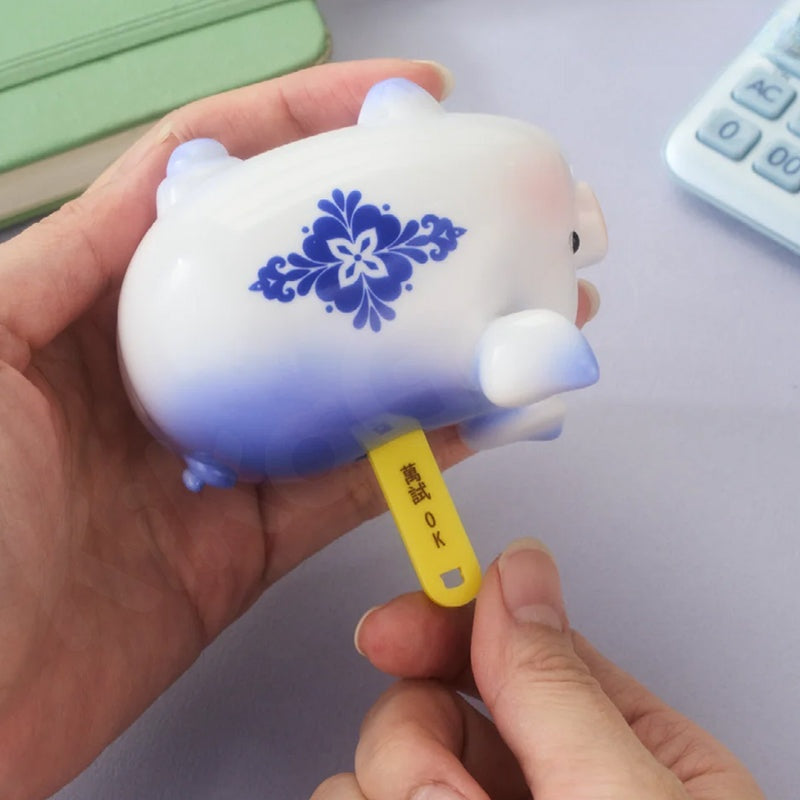 Hand holding a small white figurine with blue floral design on a light purple background