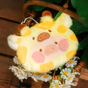 Plush keychain shaped like a cow with yellow and pink colors, surrounded by flowers and leaves.