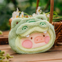 Plush toy with a green shell and pink face on a wooden surface with a blurred natural background