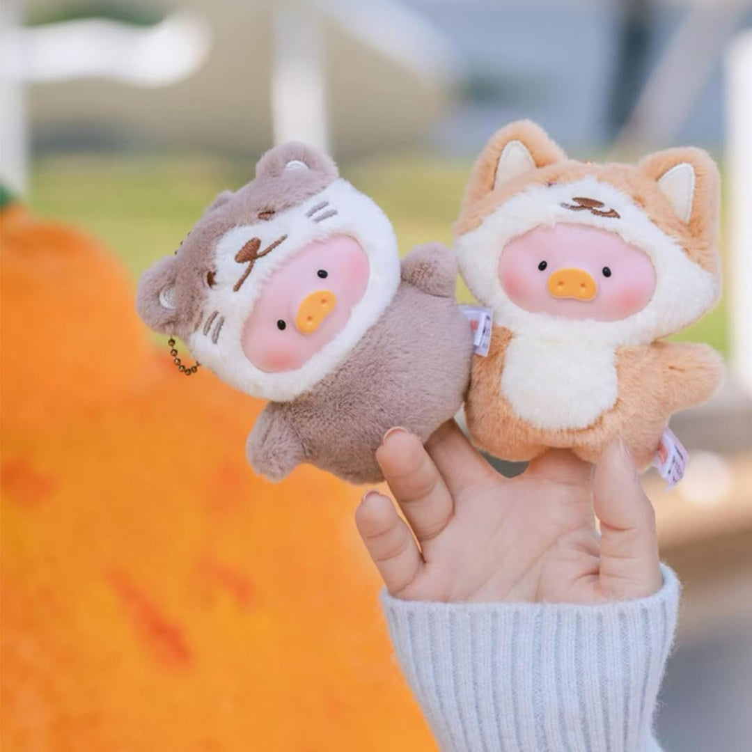 Two small plush toys held in a hand with a blurred outdoor background
