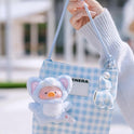 Small blue checkered bag with a plush toy attached, held by a person outdoors.