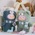 Two plush toys resembling pigs in bear costumes with scarves on a blurred background